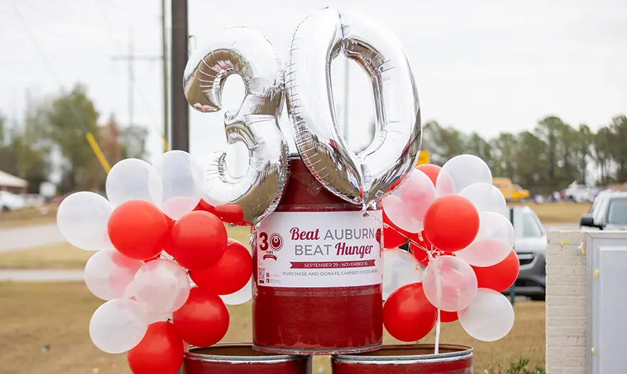 "30" balloons next to Beat Auburn Beat Hunger donation barrels