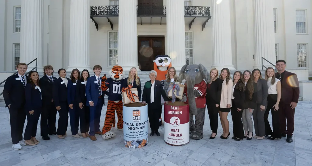 Big AL with Beat Auburn Beat Hunger barrel and Aubie with Beat Bama Food Drive barrel with their respective food drive student representatives.